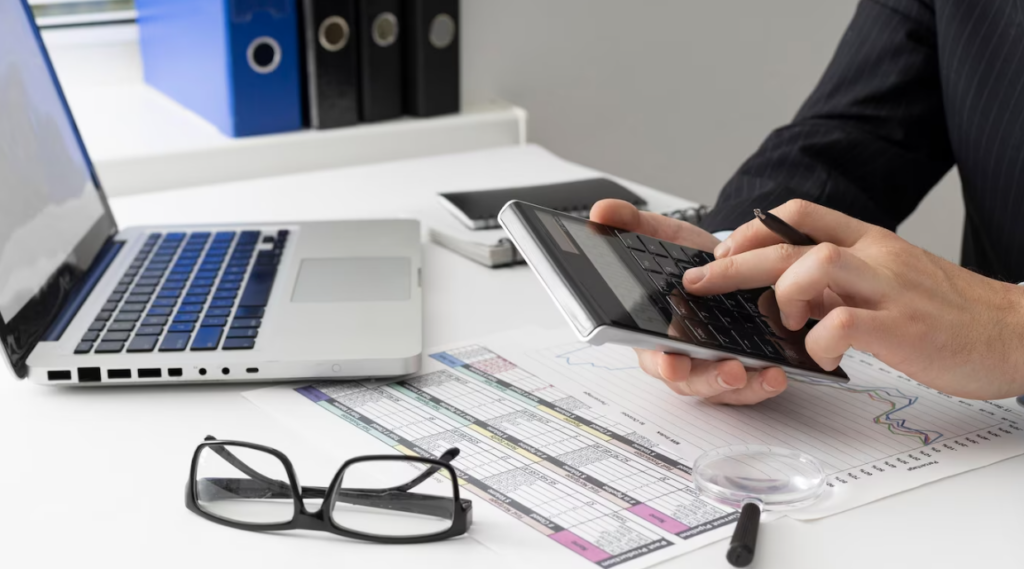 person calculating and working in the office, glasses,papers and laptop on the table