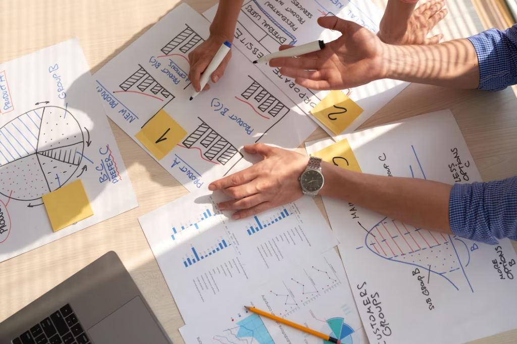 Top view of two individuals discussing business graphs drawn with marker pens.