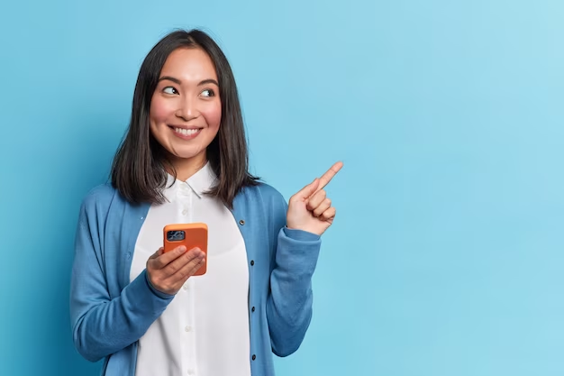 Image of a woman in a blue cardigan holding a phone and pointing to the side