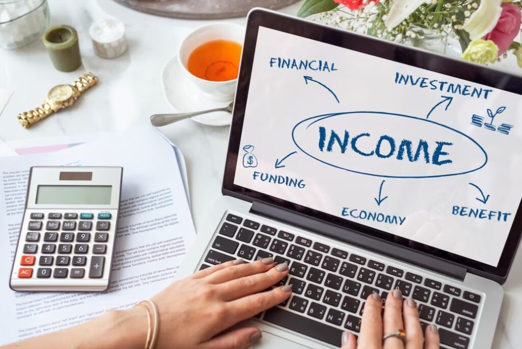 woman typing on a laptop, on which depicted word income, calculator on the table